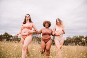 Three models in a field wearing neutral coloured underwear
