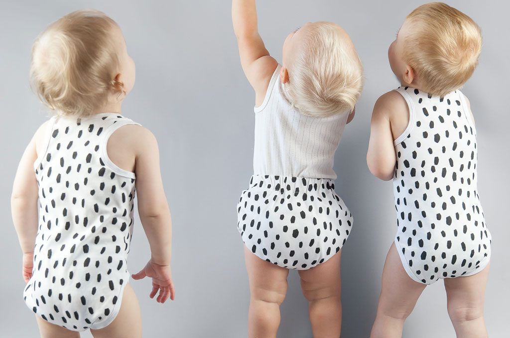 Three babies facing the wall with spotted outfits